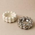 White textured ashtray and silver metallic ashtray on a beige background