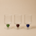 Three transparent glass with colored bases on a beige background