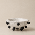 Marble bowl with black spherical bases on a beige background
