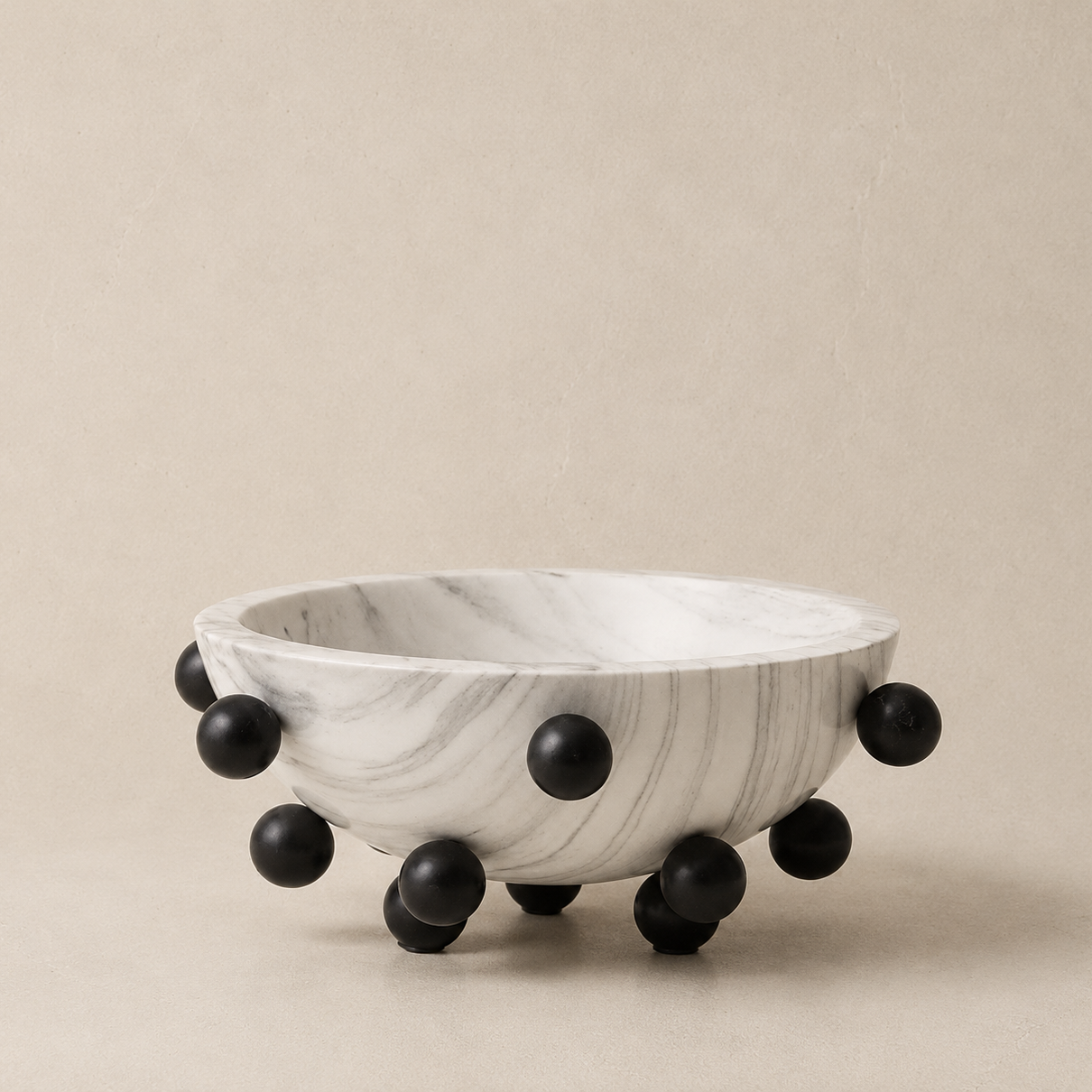 Marble bowl with black spherical bases on a beige background